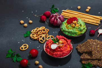 Various hummus dips, fresh vegetables and herbs. Crispy bread snacks, modern vegan healthy food