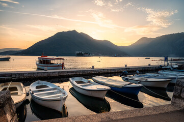 Panoramic view from the promenade of the picturesque town of Perast in the Bay of Kotor with boats on the piers at sunset, Montenegro.