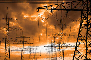  high voltage electric pylons against sky with dramatic clouds