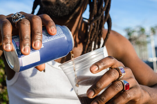 close up of unrecognizable black ethnicity person outdoors pouring beer into a plastic cup