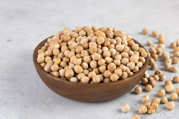Raw chickpeas in wooden bowl on gray background. High protein food. Copy space