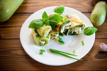 cooked zucchini rolls with cheese filling inside, in a plate