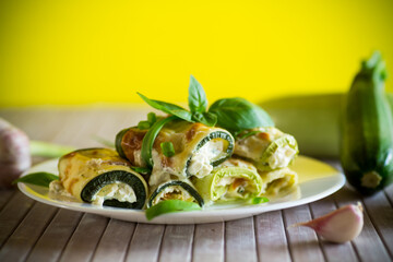 cooked zucchini rolls with cheese filling inside, in a plate