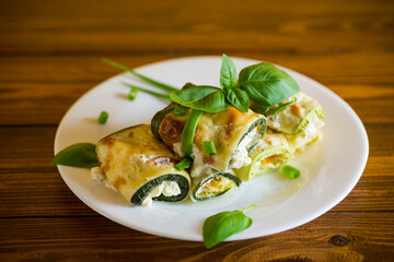 cooked zucchini rolls with cheese filling inside, in a plate