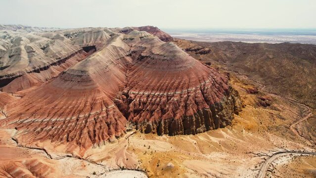 Beautiful Aktau mountains in Altyn-Emel National Park on a bright summer day. Red mountains formed by sedimentary rocks. Aerialview of sandy rocks in the wild.