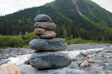 Pyramid of stones on the bank of a mountain river. Balance, relaxation symbol, zen meditation