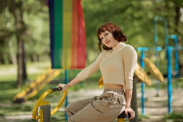 Happy and pretty lady in the park exercises the outdoor gym she looking to the camera and smiling very charismatic