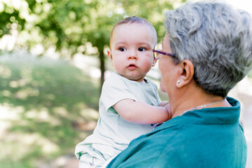 close-up shot of an unrecognizable grandmother holding her baby grandson in her arms outdoors