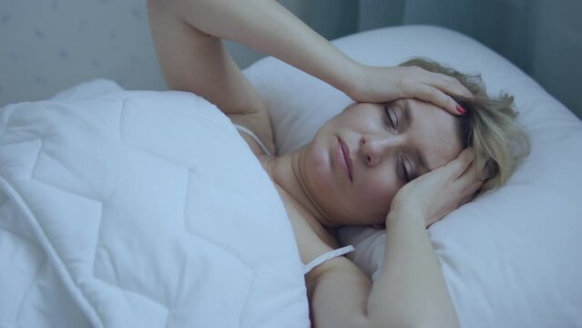 Unhappy woman can't wake up in morning because of unbearable headache, problems with blood pressure or hangover, risk of migraine attack