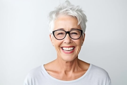 Close up portrait of smiling senior woman wearing eyeglasses standing isolated over white background