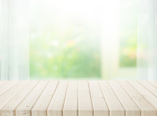 Selective focus.Wood table top on blur of window with garden flower background in morning.