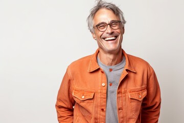 Fototapeta Portrait of a smiling senior man in orange jacket and glasses on white background obraz