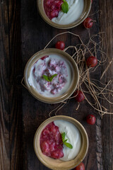 Berry yogurt dessert with gooseberry compote on wooden background