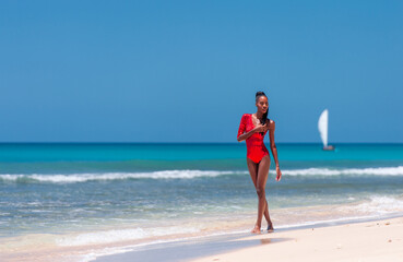 Fototapeta na wymiar Portrait of Beautiful Caribbean Adult Teen in Barbados. Wearing Red Bikini and Walking on a tropical beach. Caribbean Sea in Background. Black. Portrait.