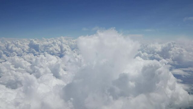Cockpit forward view when flying through Cumulus cloud formations. Bright fluffy clouds against a bright blue background. High quality cinematic 4K footage video