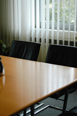 Empty conference room in hotel for business meeting with wooden table and vertical blinds during day - 620634598