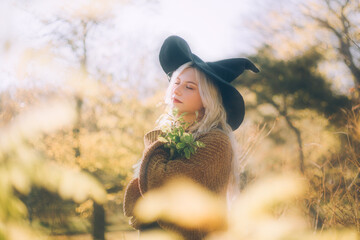 Blonde girl in a witch costume in the park