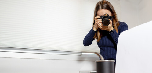 Young woman taking professional photo to object on table. Flag on one side, clear on the other....