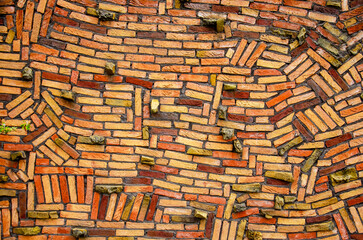 Wall with haphazardly stacked bricks in various shades of yellow, orange and red