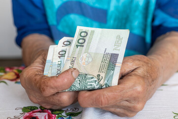 An old woman holds 100 Polish zloty banknotes in her hands, Polish money, Pensioners finance concept