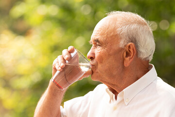 senior drinking water in summer outdoors