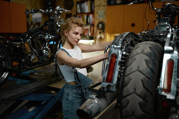 Fototapeta na wymiar Focused cycling mechanic female working at bike maintenance service