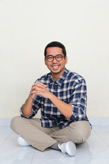 A man sitting cross legged on the floor showing happy expression