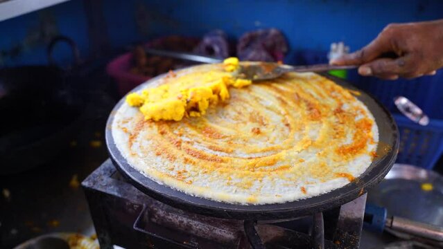 Indian Dosa street food slow motion stock footage Spreading hot chili potato stuff on famous Indian food dosa while making dosa on a hot gas stove, slow motion stock footage