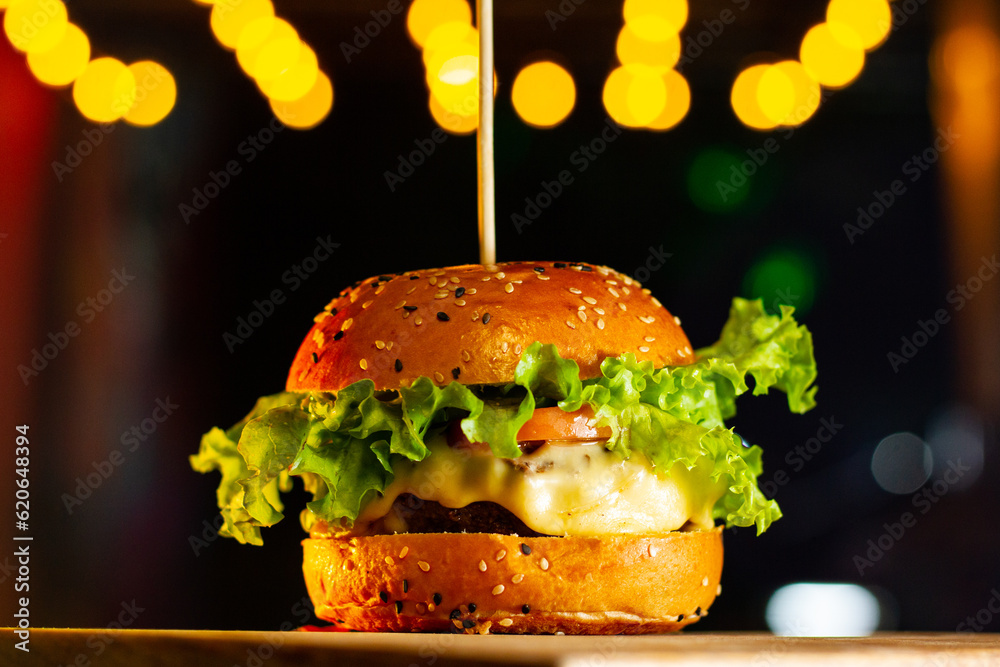 Wall mural cheeseburger with lettuce and tomato at a night scene