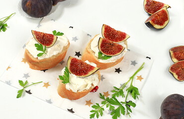 Healthy breakfast with ingredients, toast with figs and soft cream cheese and honey, Canape or crostini with fried baguette and herbs on a light sunny table, italian recipes menu, selective focus