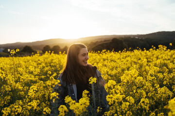 Happy Young woman in flowers field during sunset