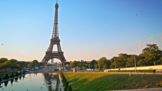 The romantic city of Paris at golden sunset with birds in the sky. View of the historical Tower from the Trocadero Garden with the reflection in the water of the fountain.