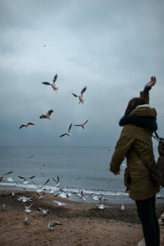 Woman looking at seagulls flying over the stormy sea 