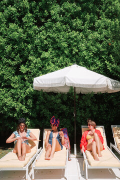 women relaxing poolside in loungechairs