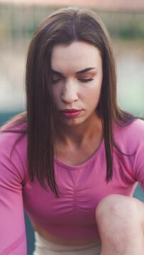 Vertical video. Young motivated girl is preparing to run stadium in summer, heathy lifestyle, sport conception. Portrait of a girl runner before the race