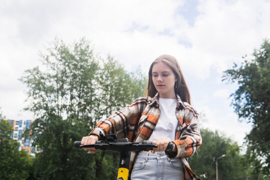 young woman on an electric scooter rides down the street