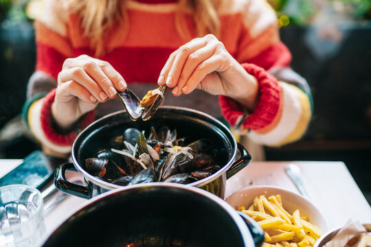 Faceless woman eating mussels in restaurant