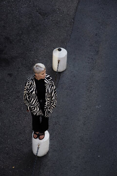 Woman standing on a concrete fence post outdoor