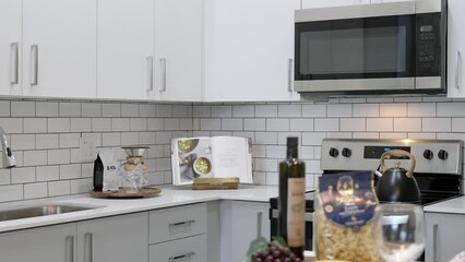 Stunning interiors of exquisite kitchen completed with new furniture, delicate pieces of crockery and modern appliances. Minimalist atmosphere in white color