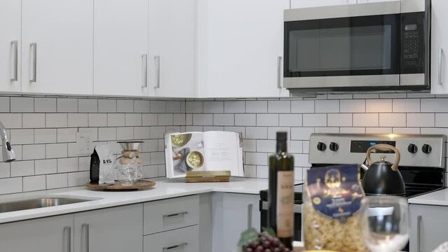 Stunning interiors of exquisite kitchen completed with new furniture, delicate pieces of crockery and modern appliances. Minimalist atmosphere in white color