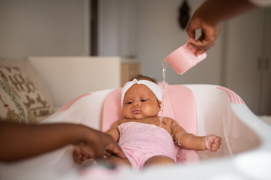 Black woman washing daughter in baby bath