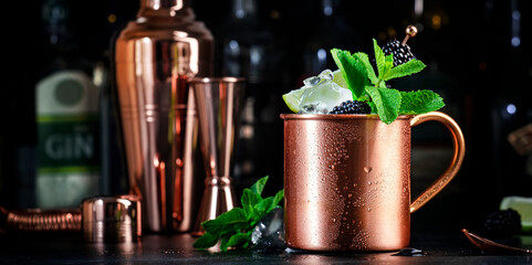 Blackberry Moscow mule alcoholic cocktail drink in copper mug with lime, ice, ginger beer, vodka...