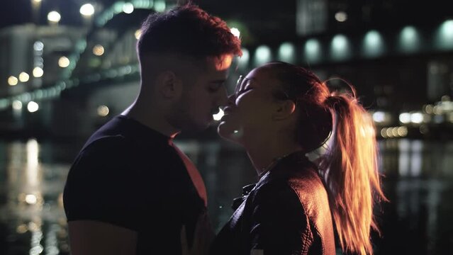 Affectionate couple kissing on illuminated city street at night