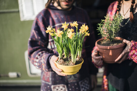 Young copule holds flowers in the pot
