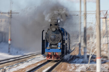 Tourist retro steam locomotive arrives at the station in a puff of smoke