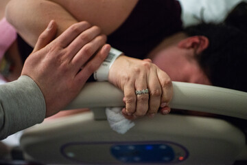 Male hand touching arm of pregnant woman giving birth