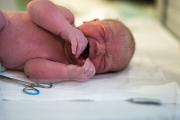 monochrome image of undressed newborn baby crying