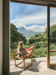 Woman relaxing in a chair on a balcony with mountain views