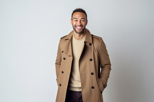 Young african american man in trench coat smiling at camera.