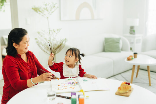 smiling mature grandmother and granddaughter drawing